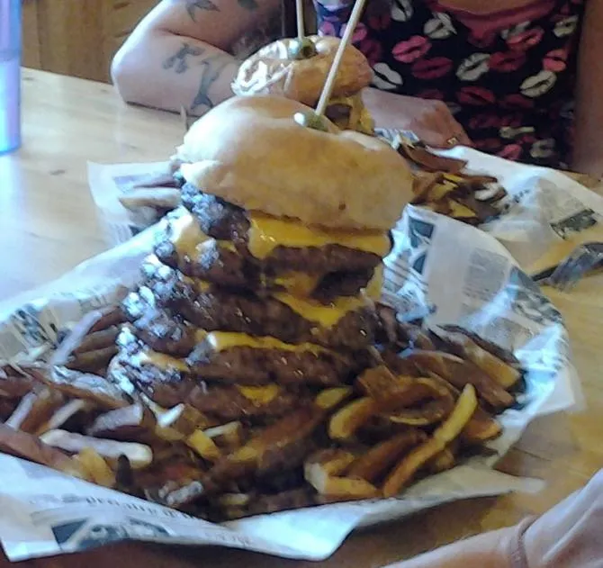 Gronk's Great Divide burger tower with fries on a wooden table